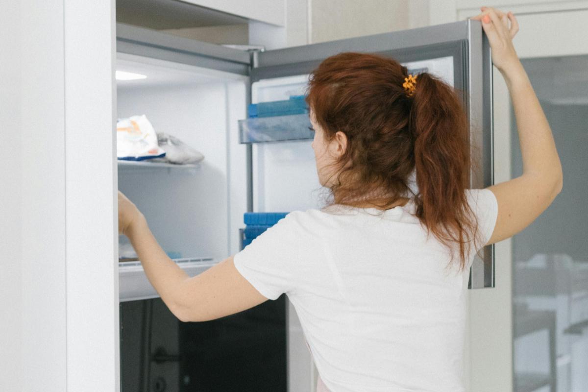 donna che guarda dentro al freezer