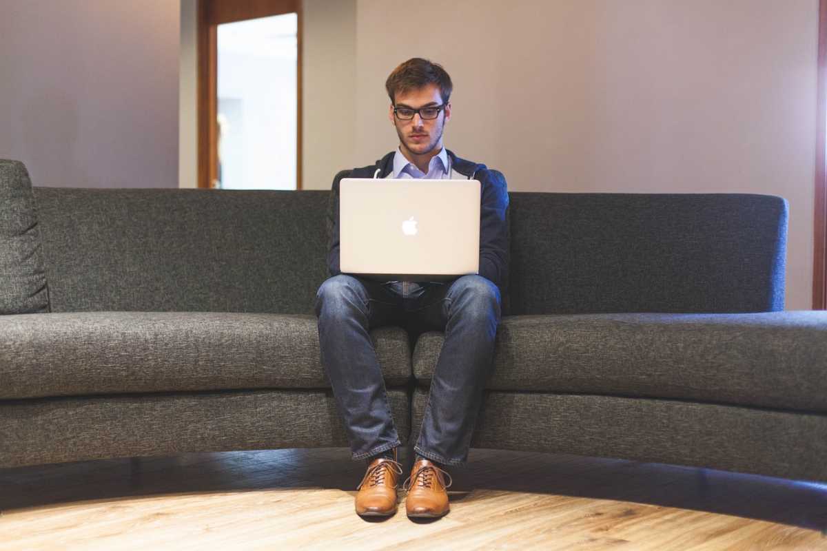 ragazzo seduto sul divano con il computer sulle ginocchia