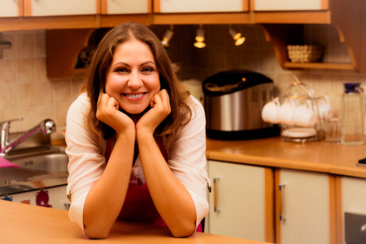 donna che sorride con i gomiti sul mobile della cucina