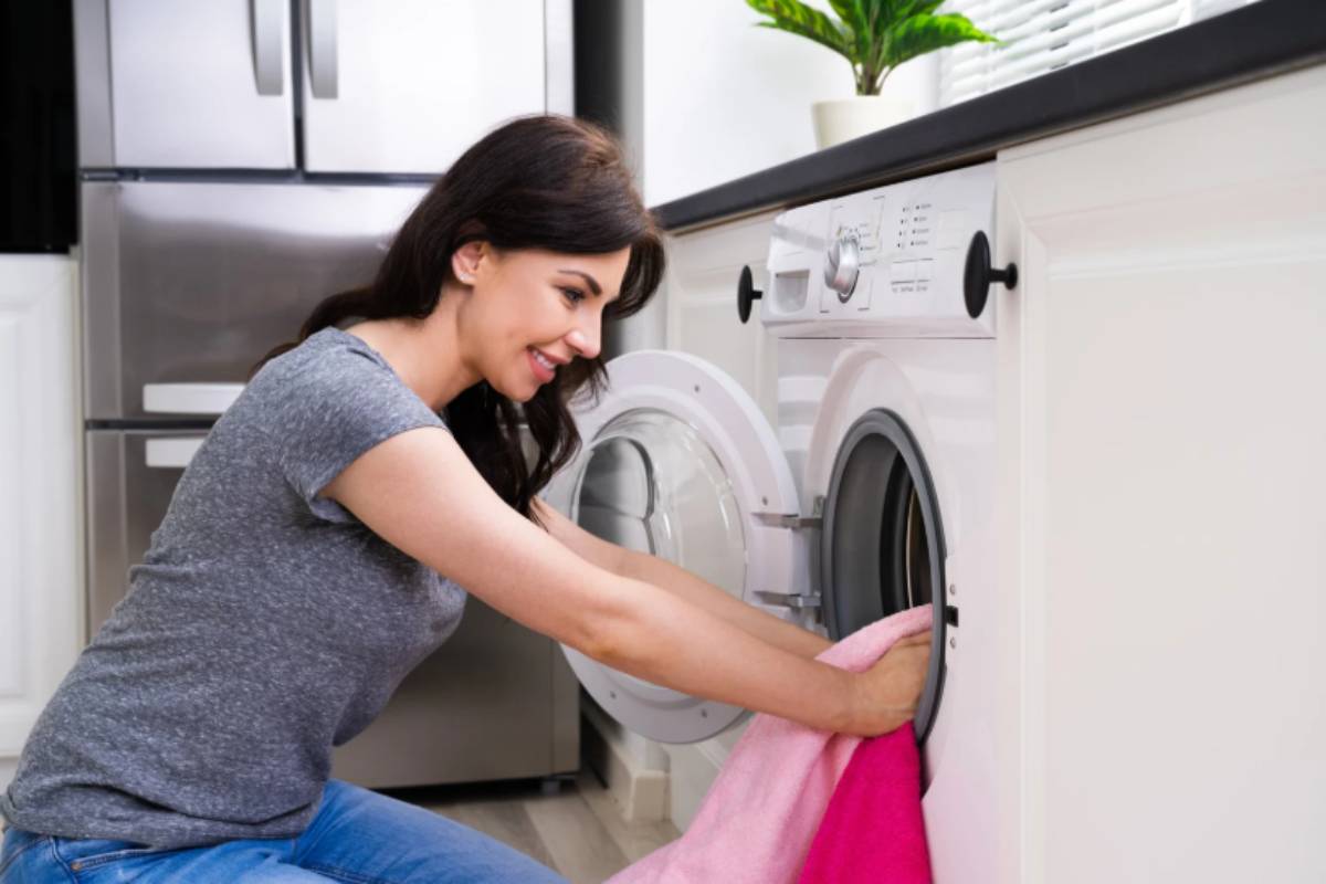 donna che sorride mentre ritira il bucato dalla lavatrice