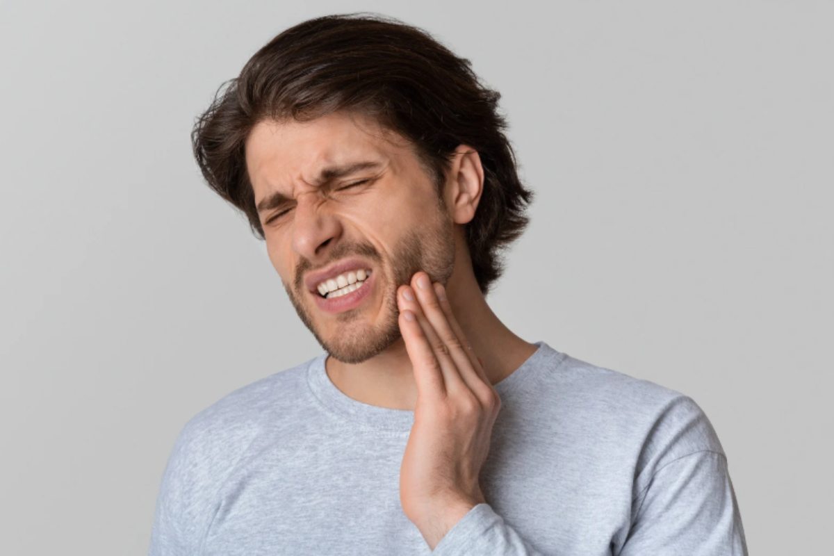 uomo con il mal di denti che si tocca una guancia