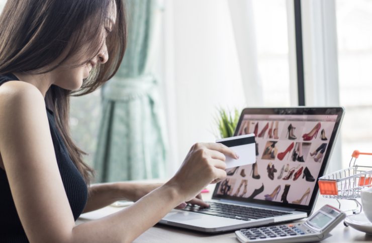 ragazza che fa shopping online con davanti un computer e in mano una carta di credito