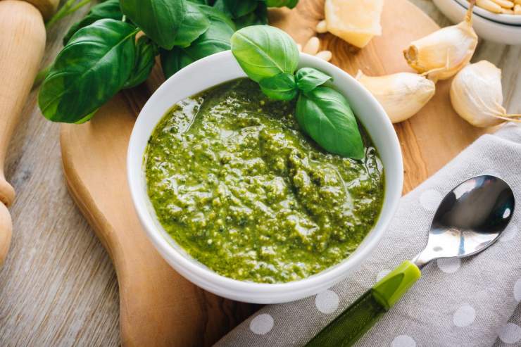 pesto genovese in una ciotola con vari ingredienti attorno