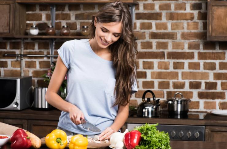 donna che taglia le verdure e sorride