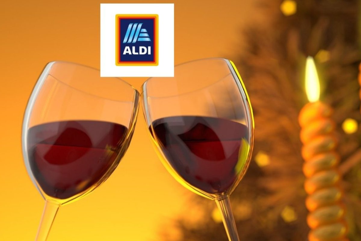 calici che brindano pieni di vino rosso e dietro una candela