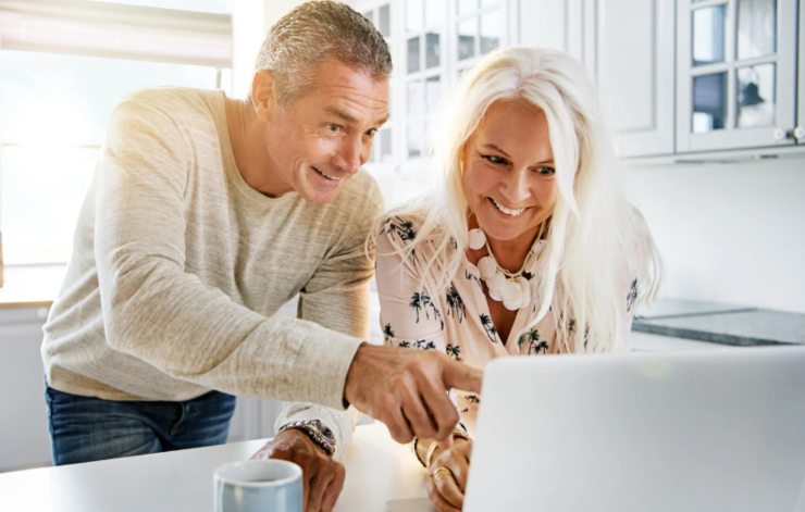 uomo e donna che sorridono mentre guardano qualcosa sul computer