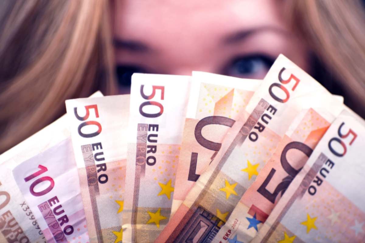 ragazza con delle banconote di euro davanti al viso