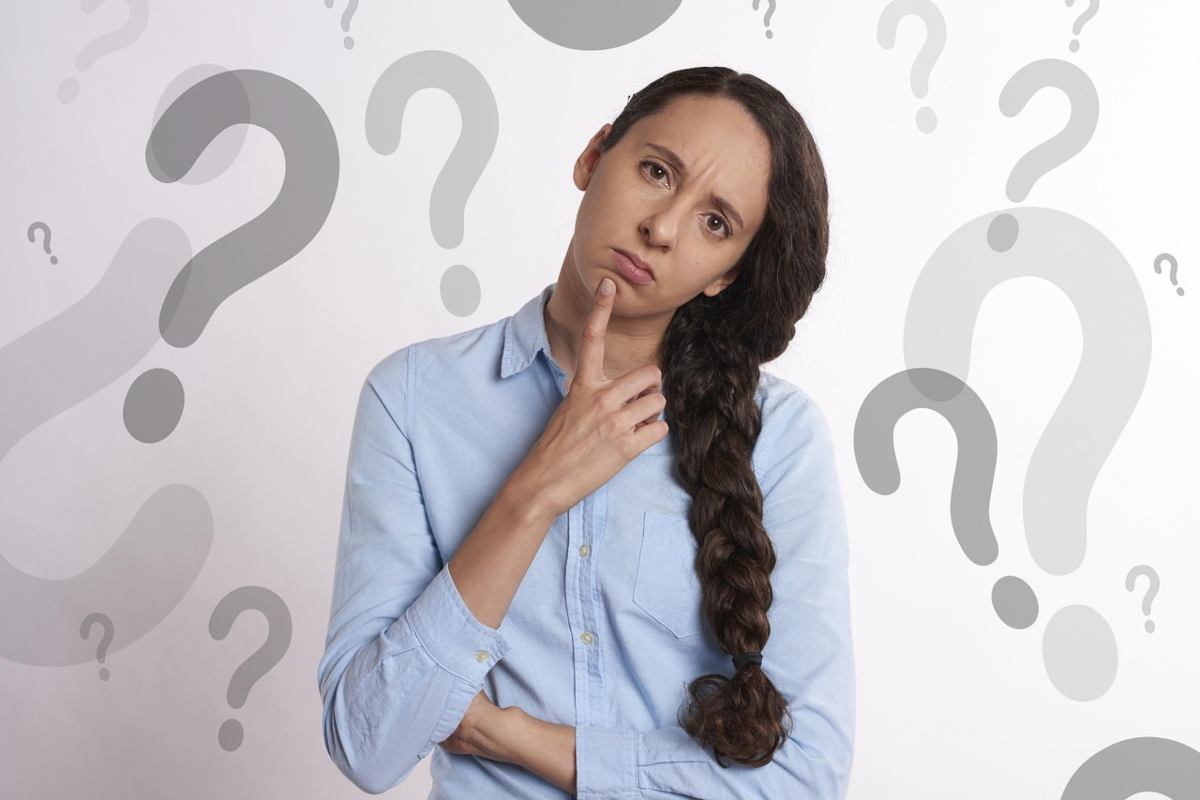 donna con un dito vicino alla bocca circondata da punti interrogativi