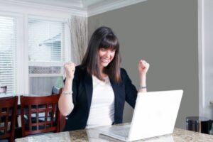 donna felice che esulta seduta davanti al computer