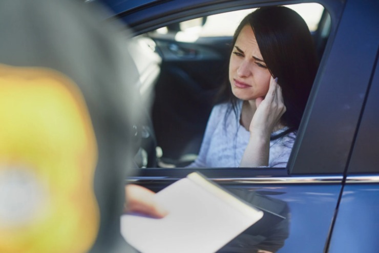 donna in auto al cellulare e agente che le fa la multa