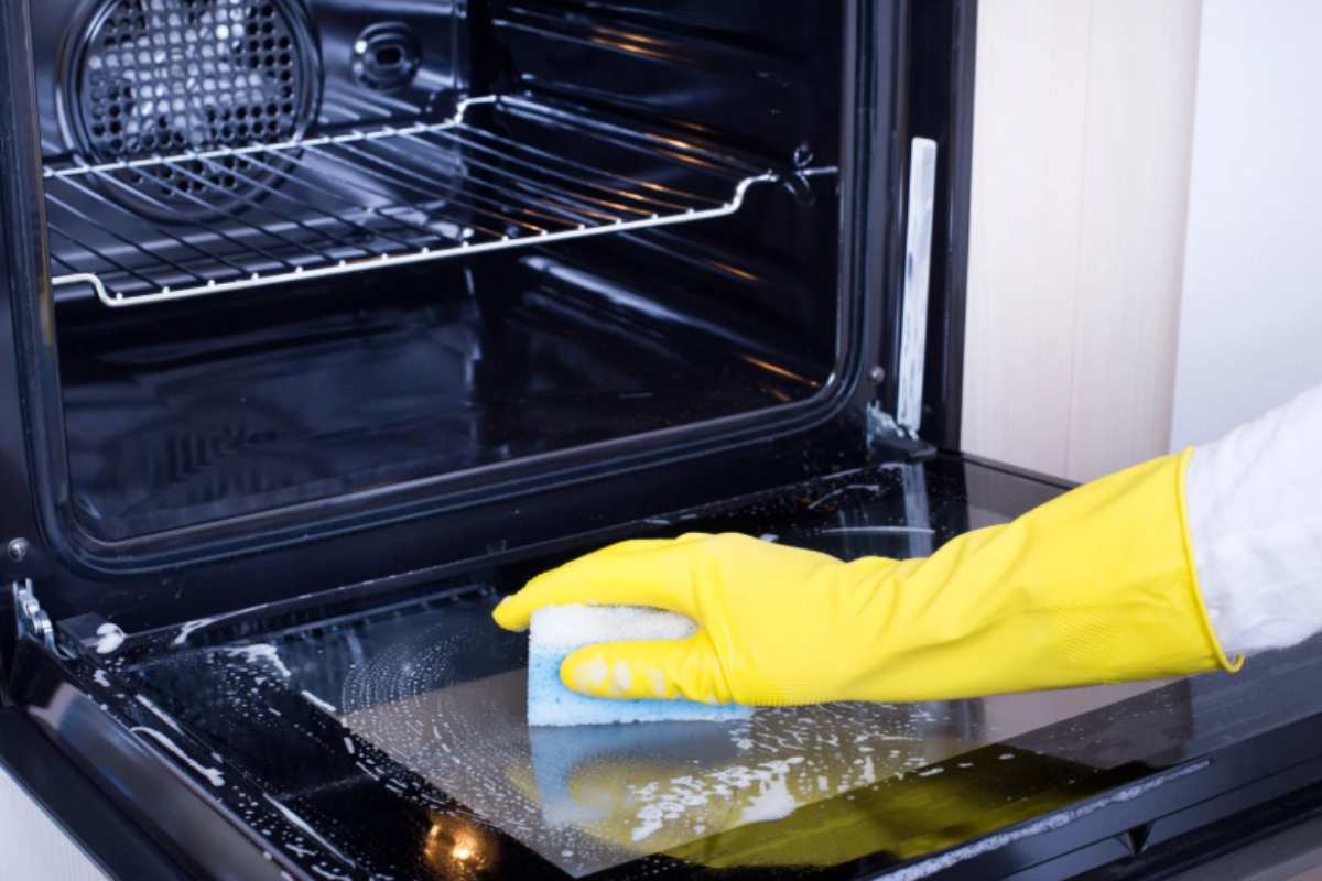donna che pulisce il forno con una spugnetta