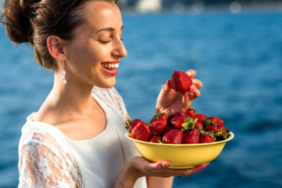donna con in mano una ciotola piena di fragole
