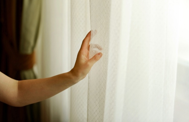 persona che sposta le tende di casa