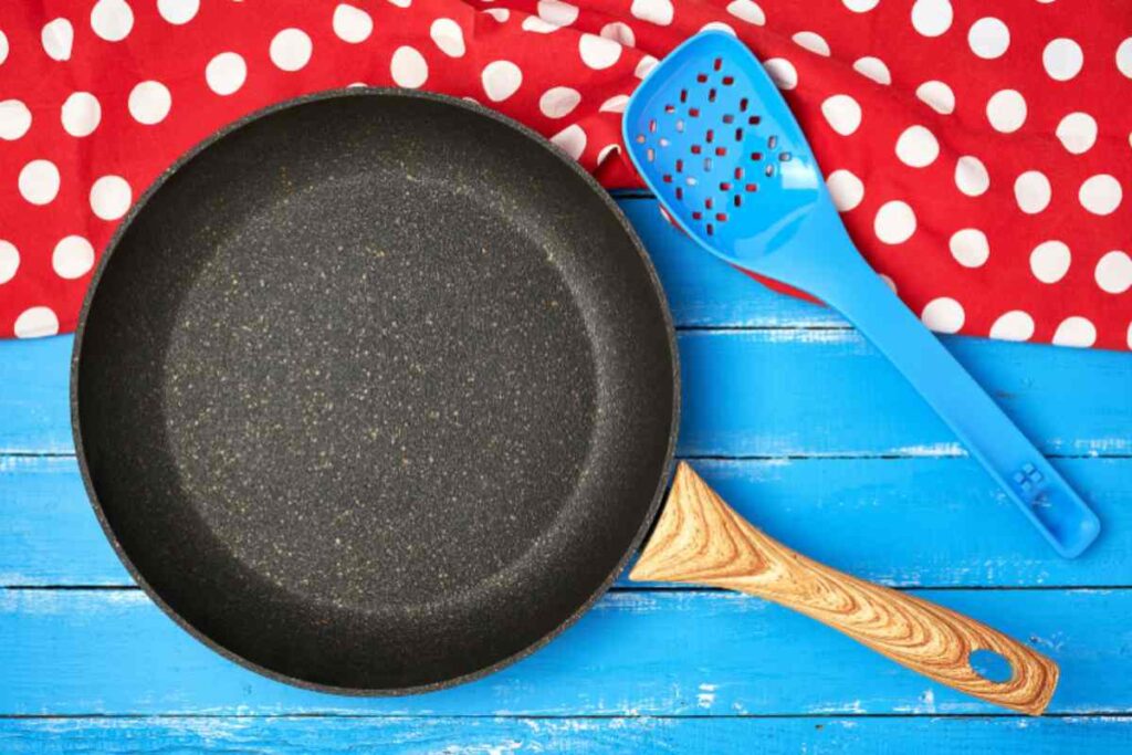 padella con accanto un mestolo di plastica azzurro