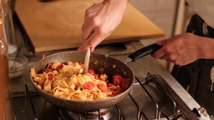 persona che sta cucinando della pasta in padella