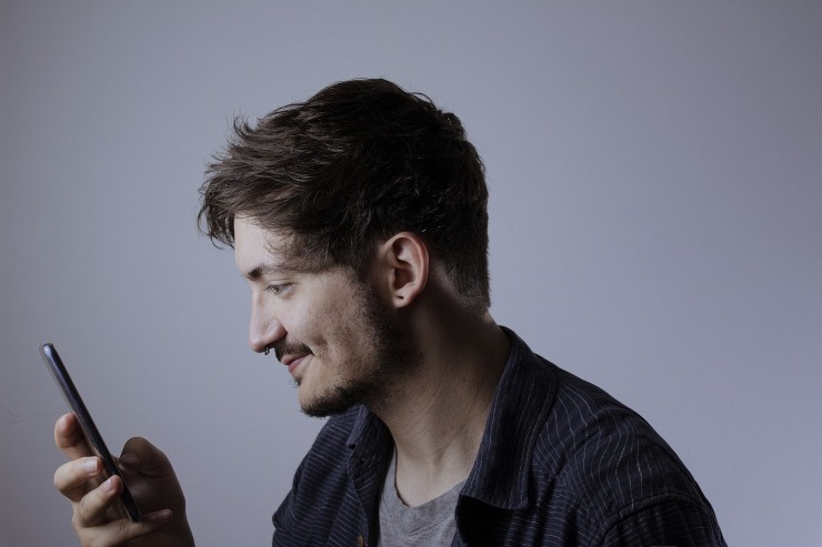 ragazzo che sorride con il cellulare in mano