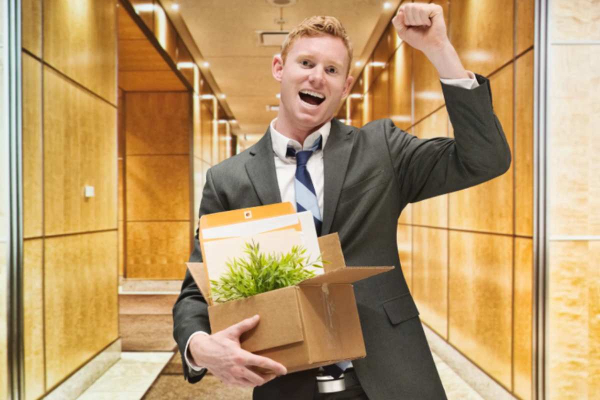 uomo felice che va via dall'ufficio con uno scatolone in mano