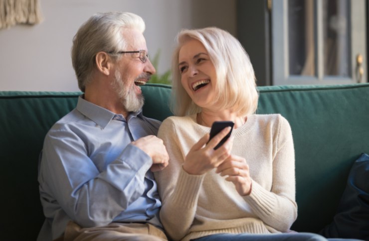 uomo e donna anziani che sorridono seduti sul divano