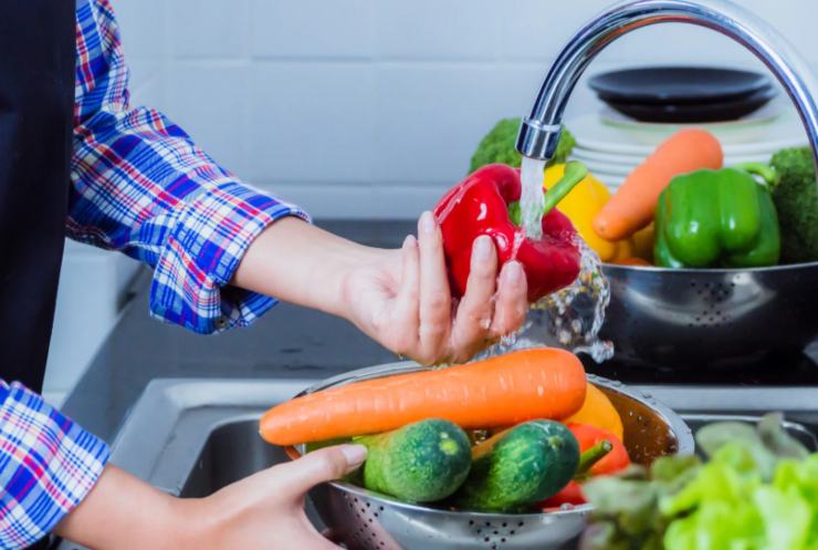 persona che sciacqua le verdure sotto l'acqua