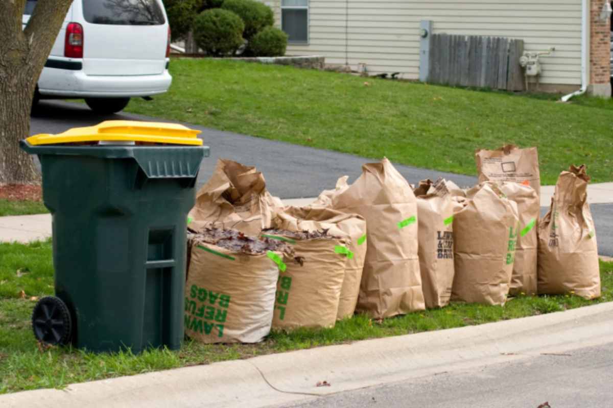 bidone dell'immondizia con accanto tanti sacchetti pieni di rifiuti