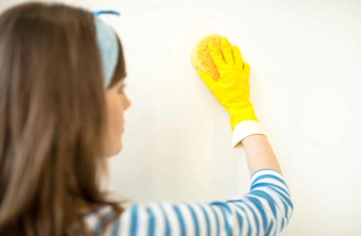 donna che pulisce un muro con una spugna