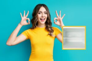 donna che sorride e fa ok con le dita e nel riquadro un freezer senza brina