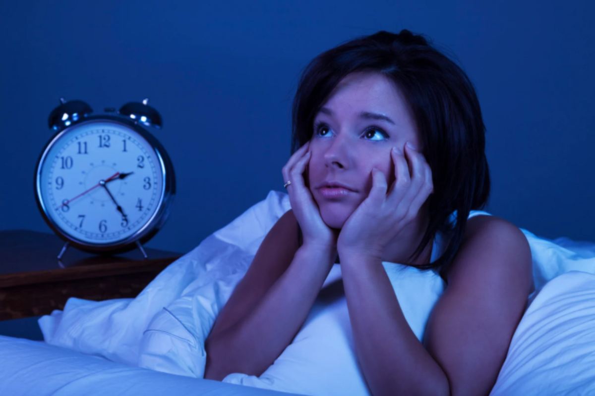 donna a letto che non riesce a dormire e accanto una sveglia