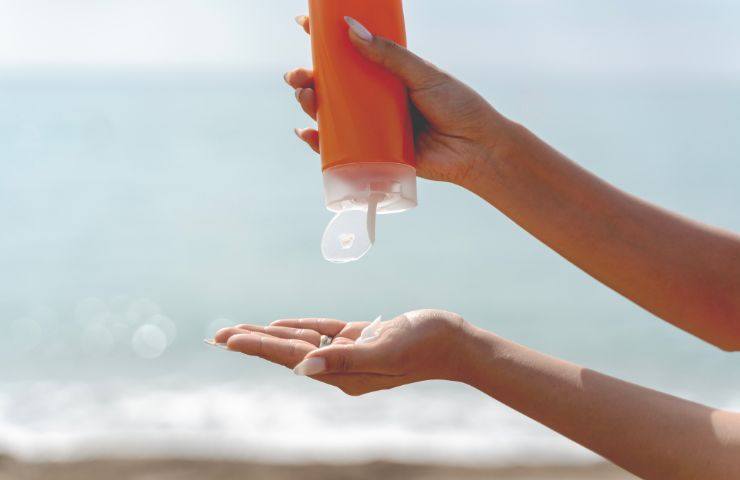 donna mette crema solare al mare