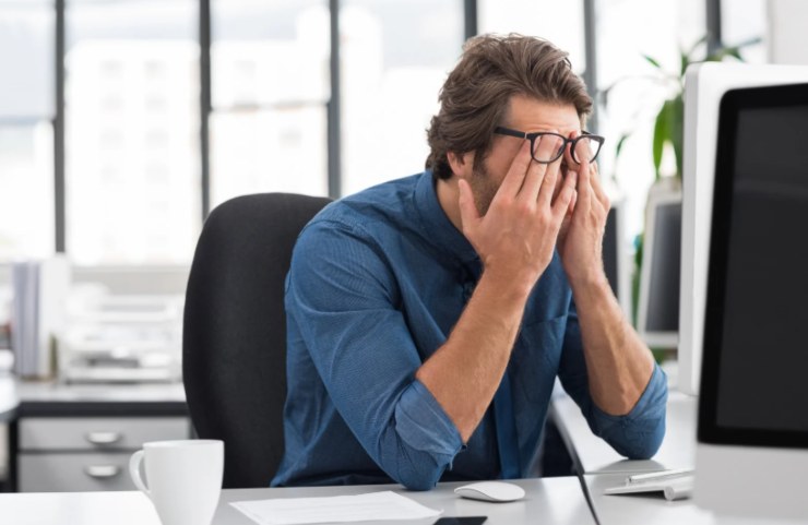 uomo preoccupato davanti al computer con la mani in faccia