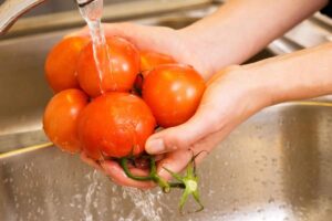 mani che sciacquano pomodori