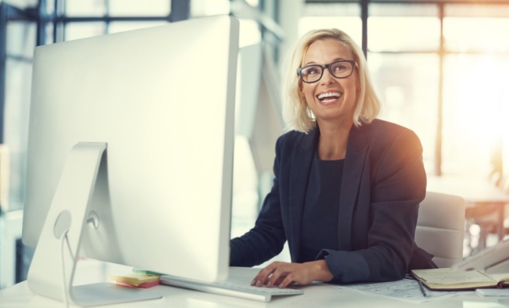 donna sorridente seduta davanti al computer