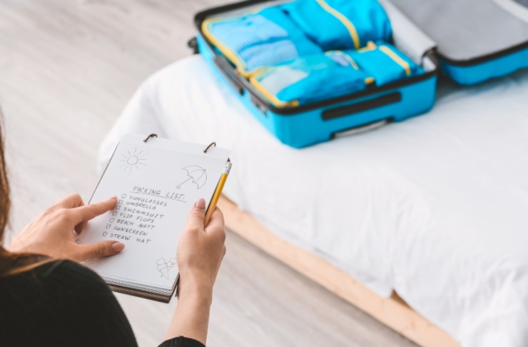 valigia sul letto e donna che legge una lista su un quaderno