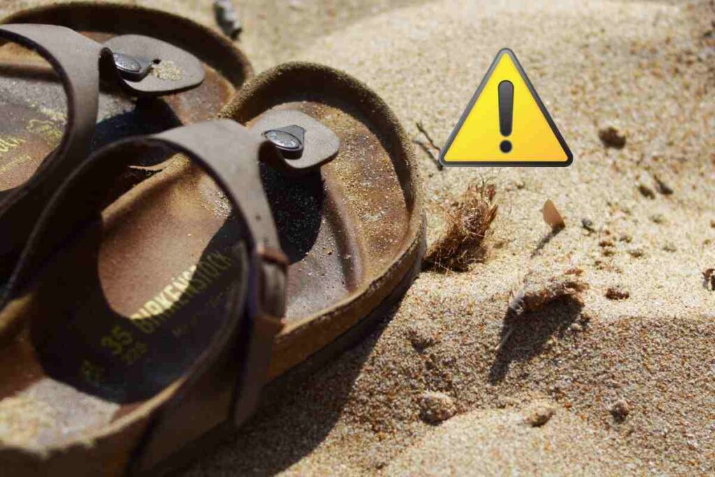 birkenstock in spiaggia e simbolo attenzione