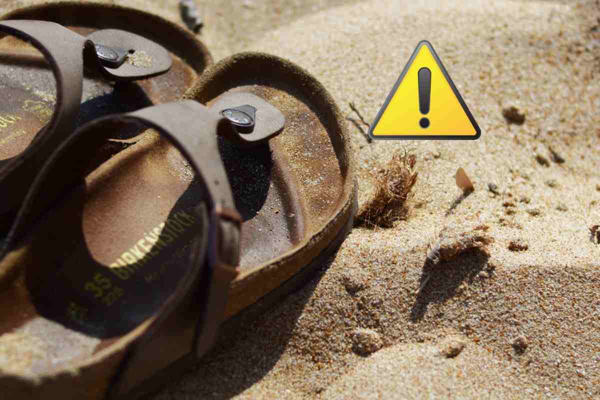 birkenstock in spiaggia e simbolo attenzione