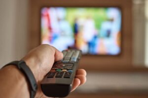 Persona che punta telecomando verso TV accesa