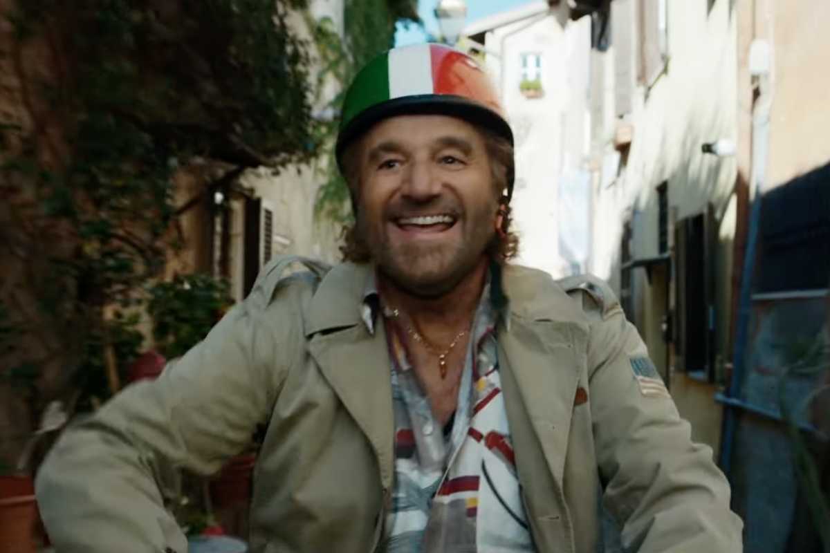 Christian De Sica sul motorino con casco