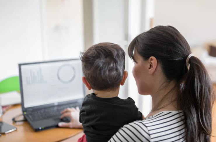 donna al pc con bimbo in braccio