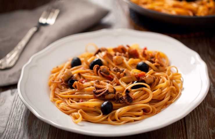 un piatto di pasta con moscardini e olive nere