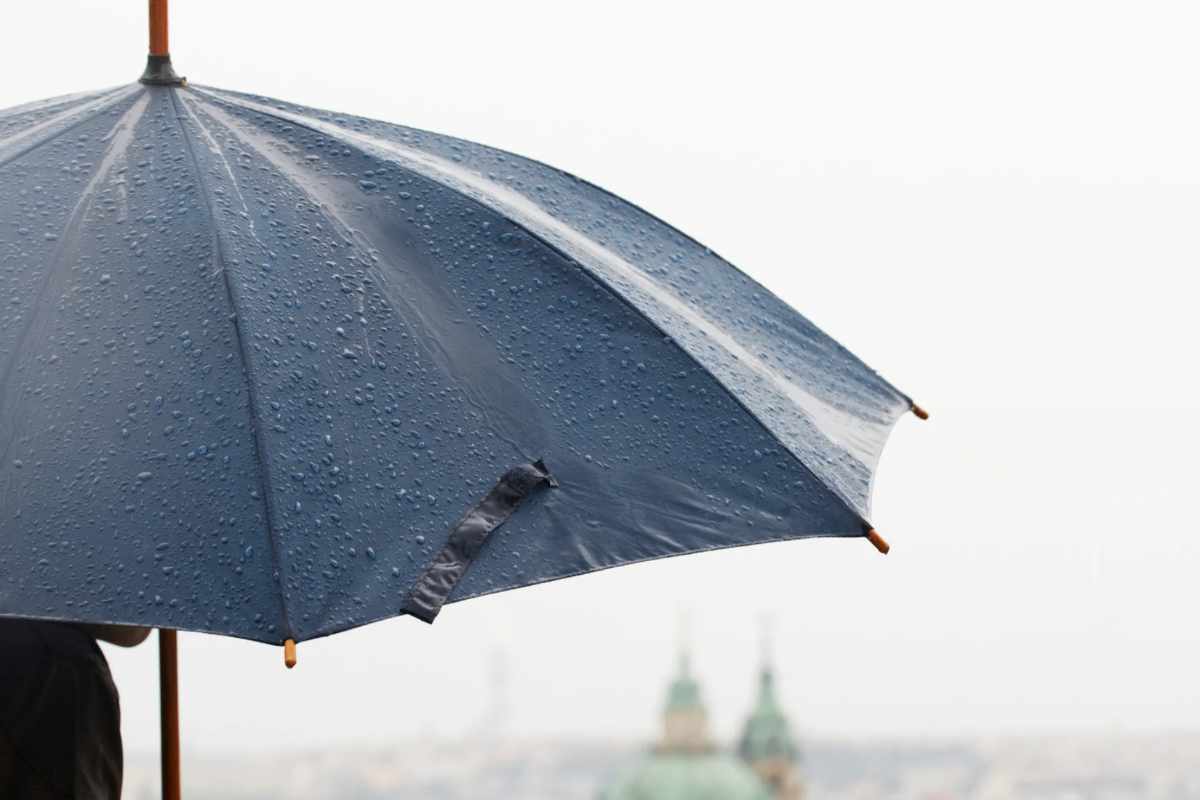 Persona che tiene ombrello bagnato aperto