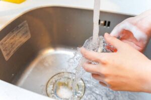 Persona che lava bicchiere nel lavandino