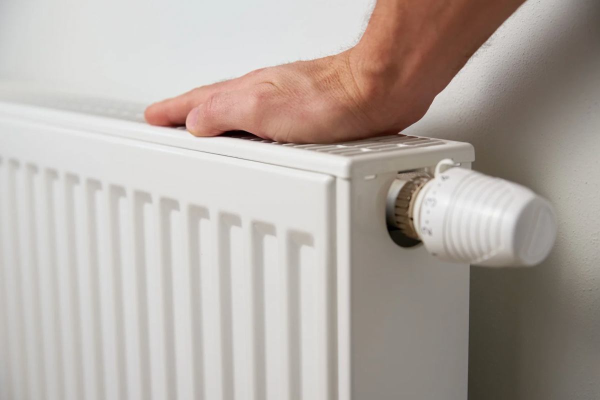 Person a che poggia la mano sul termosifone