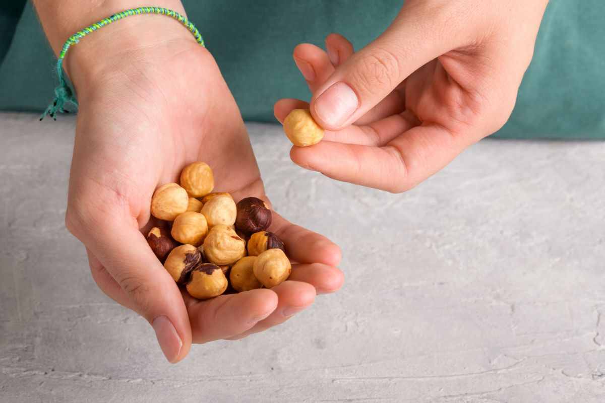 mani con nocciole sbucciate