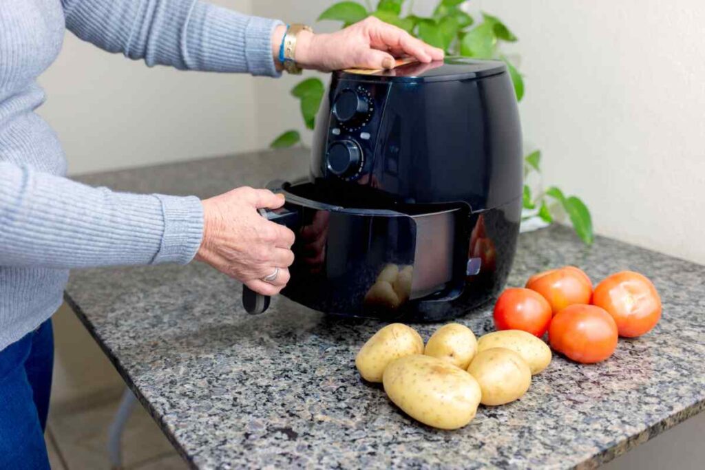 Donna che apre cestello della friggitrice ad aria