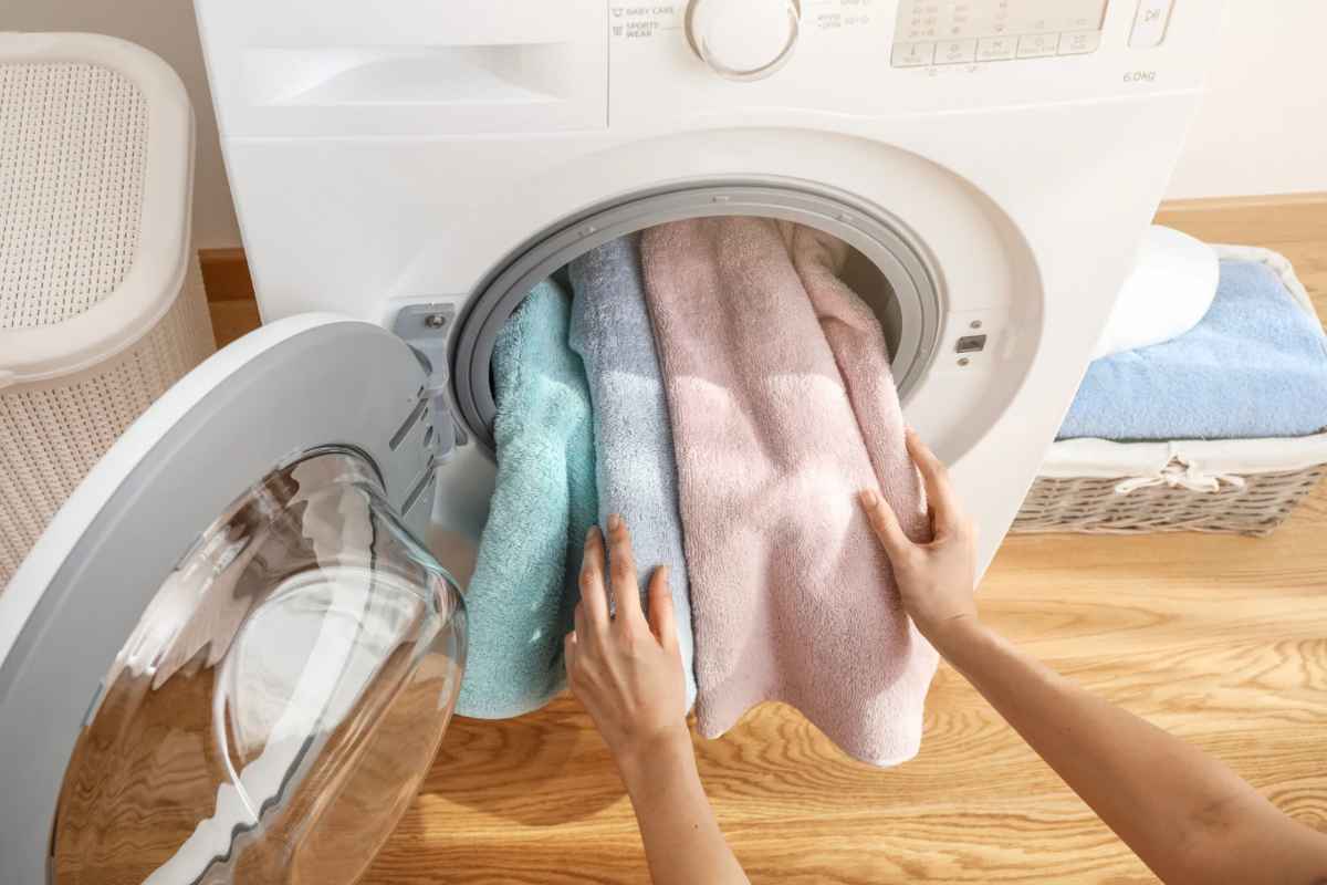 Donna che mette asciugamani colorati nella lavatrice