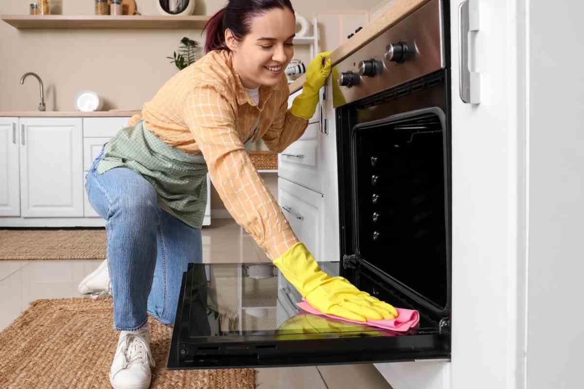 donna che pulisce lo sportello del forno