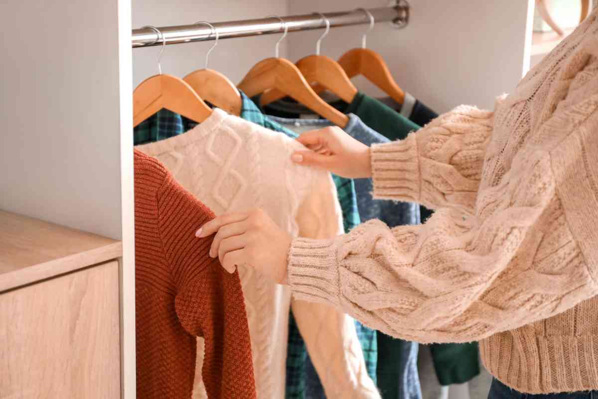 Donna che prende in mano maglioncini con stampelle