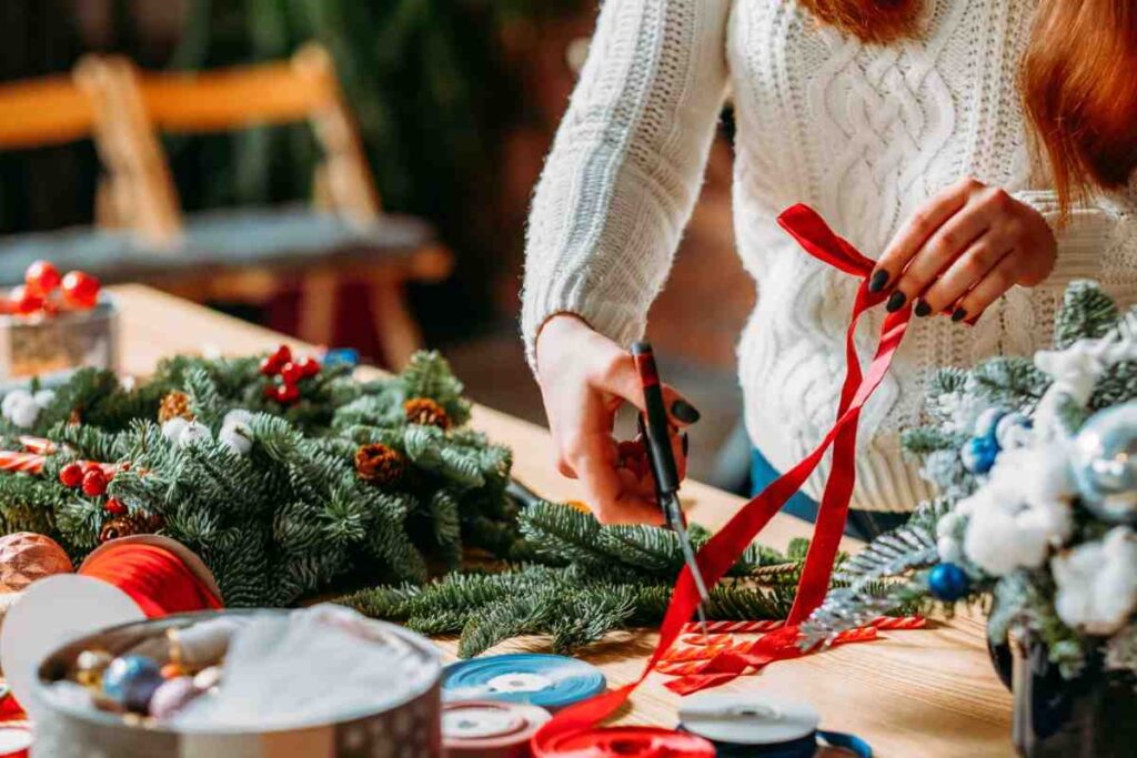 Donna che crea decorazioni di Natale con nastro rosso