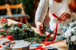 Donna che crea decorazioni di Natale con nastro rosso