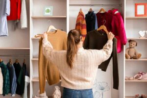 Donna che prende capi d'abbigliamento dall'armadio