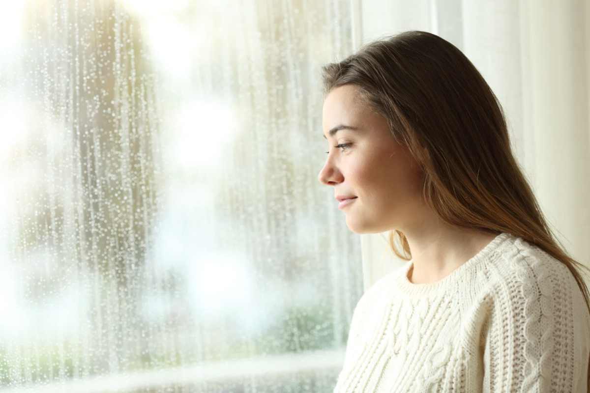 Donna che guarda fuori dalla finestra mentre piove